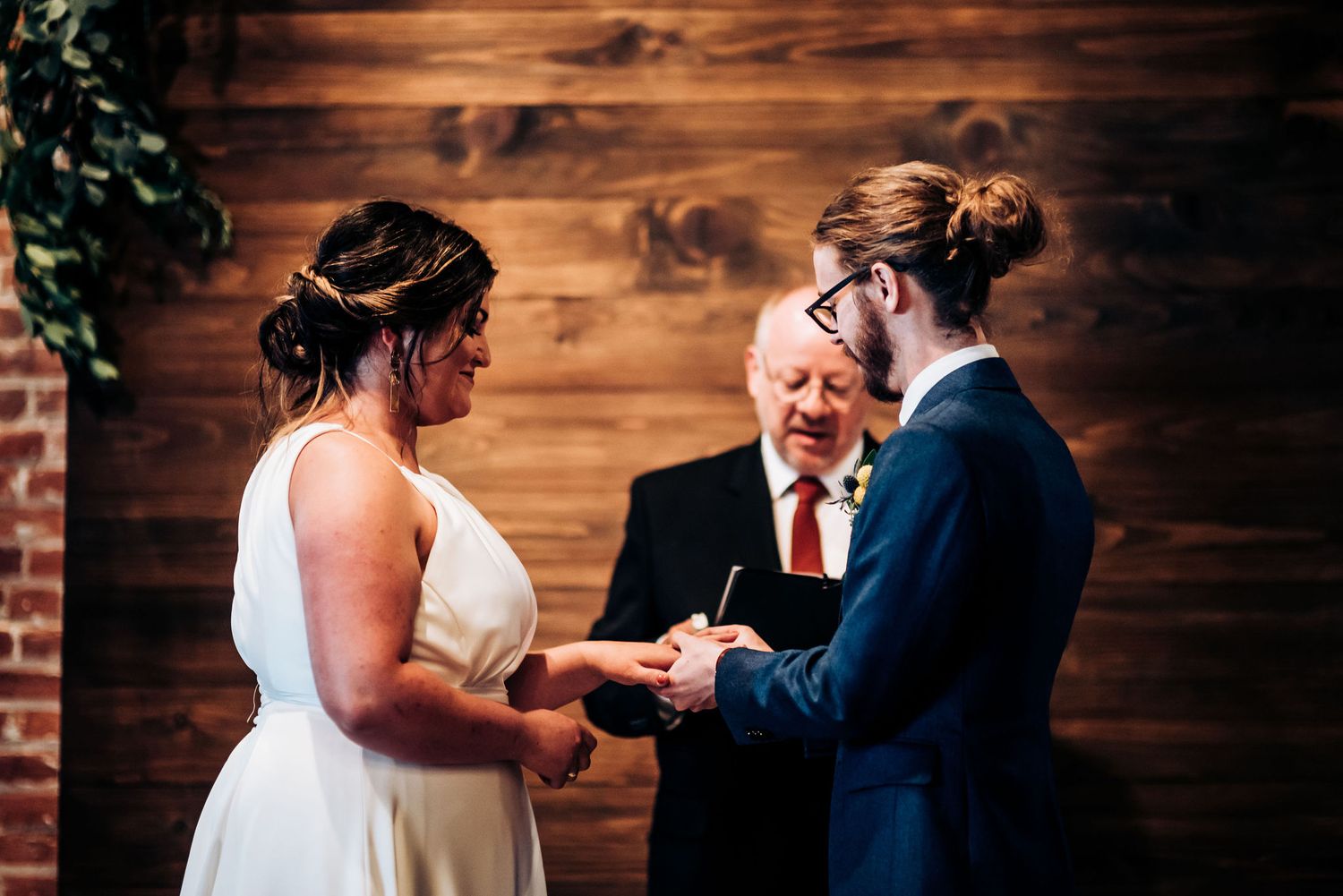 A couple exchanges rings during intimate wedding ceremony with officiating minister.