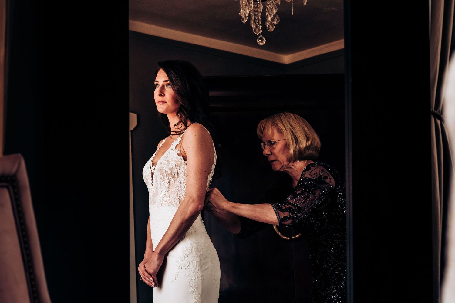 Wedding dress fitting scene with elegant white gown in dimly lit room.