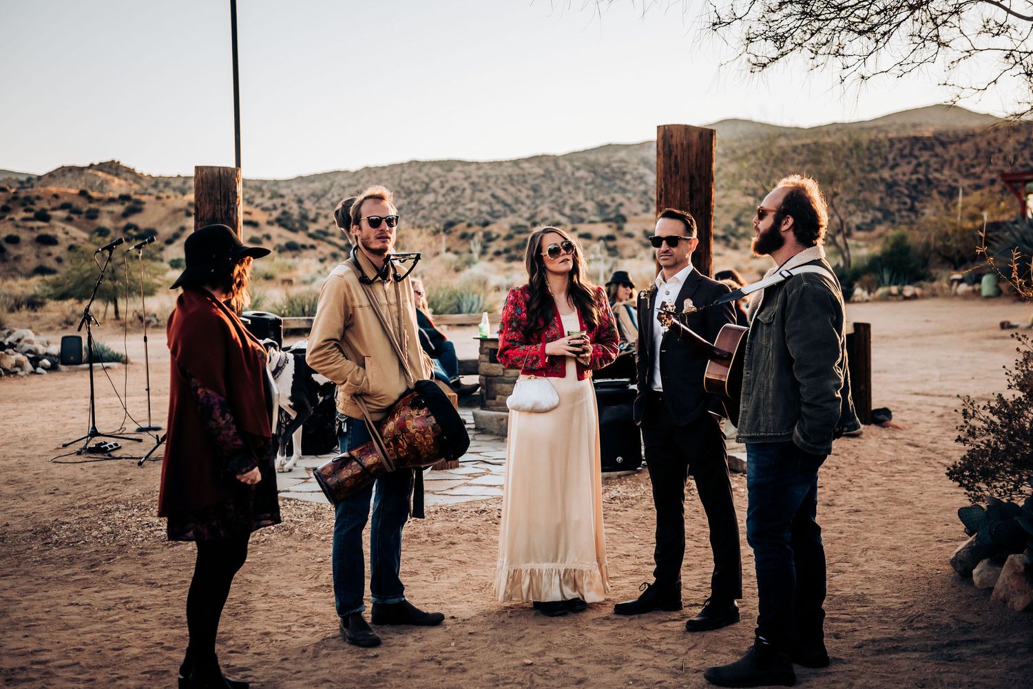 An outdoor desert wedding ceremony with musicians and guests gathered in scenic surroundings.
