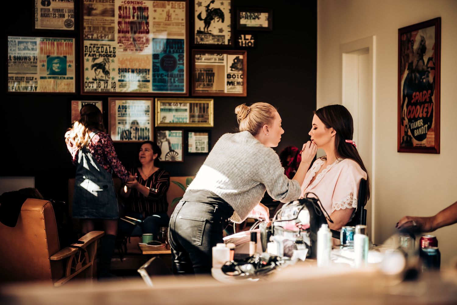 Preparation scene in dressing room with makeup products and vintage posters on wall.