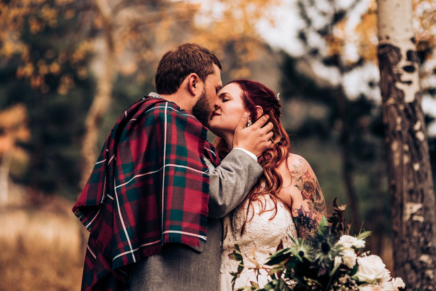 Romantic autumn wedding moment among birch trees in mountain setting.