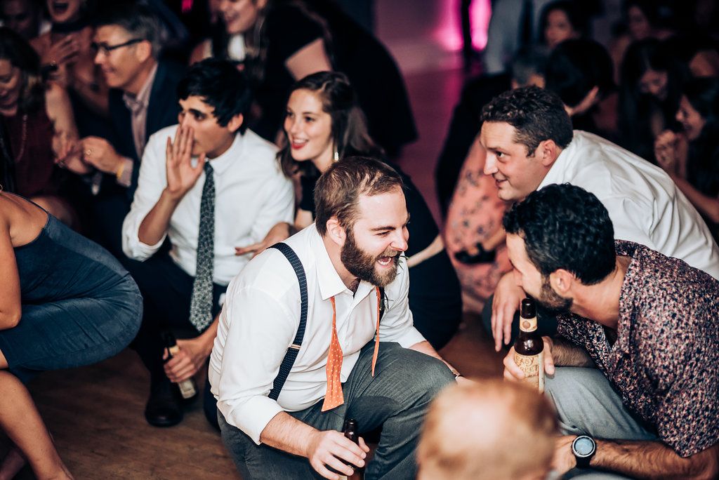 Party guests crouching low on the dance floor during an energetic dance moment.