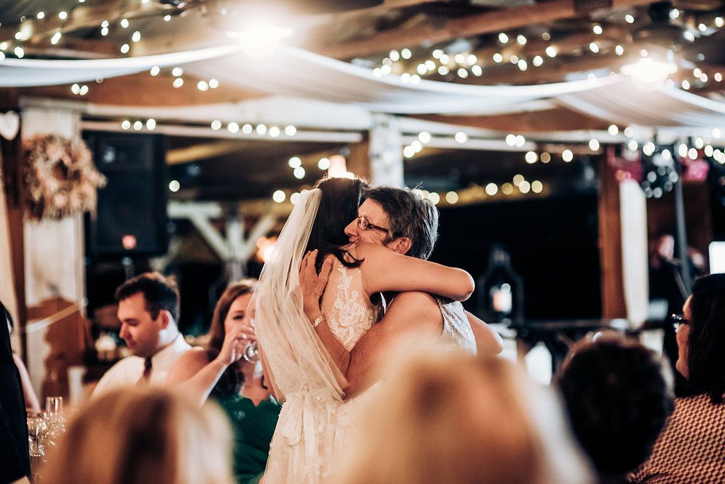 A tender dance moment captured at a wedding reception under glittering string lights.