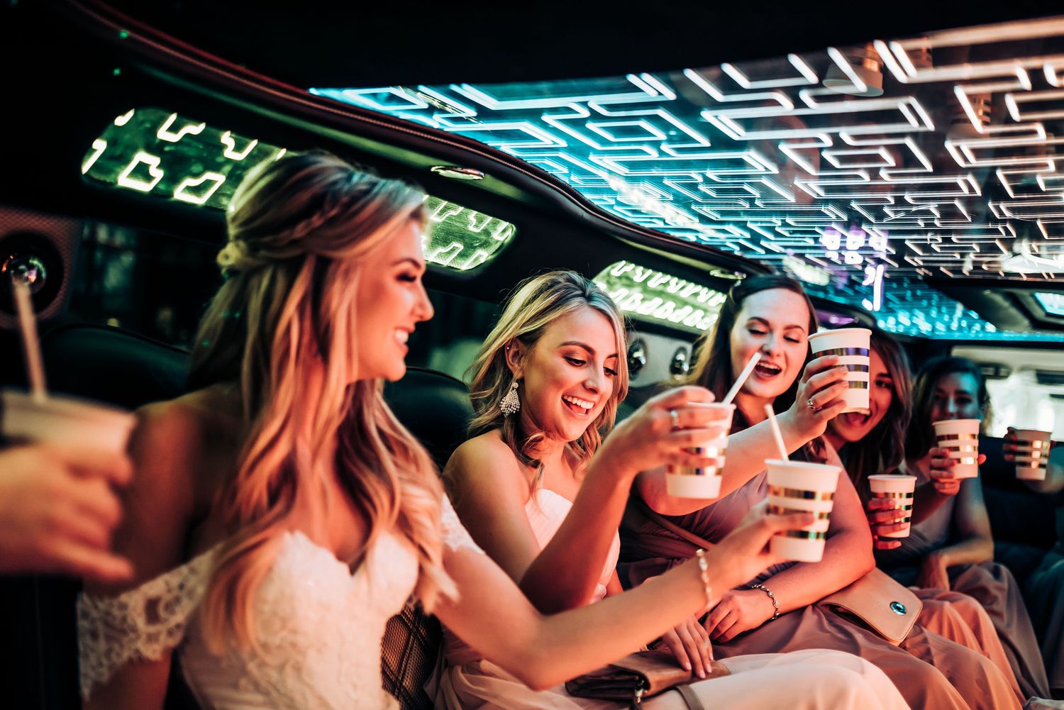 A lively party scene in a limousine with people enjoying drinks under blue neon lighting.
