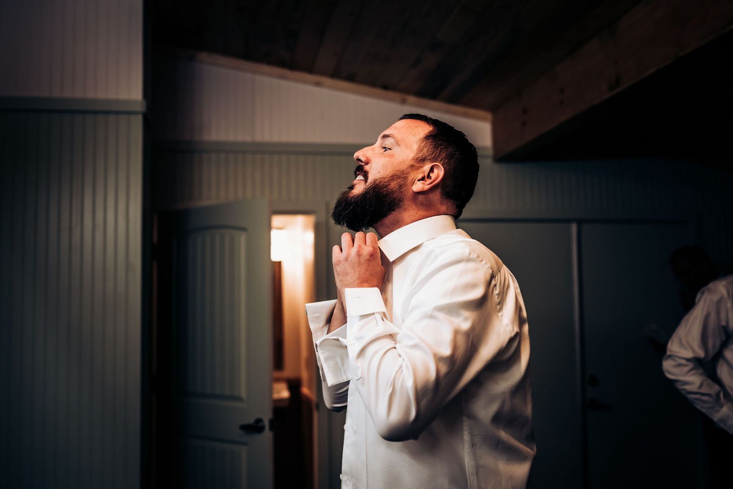 Person in white dress shirt adjusting collar while looking to the side.