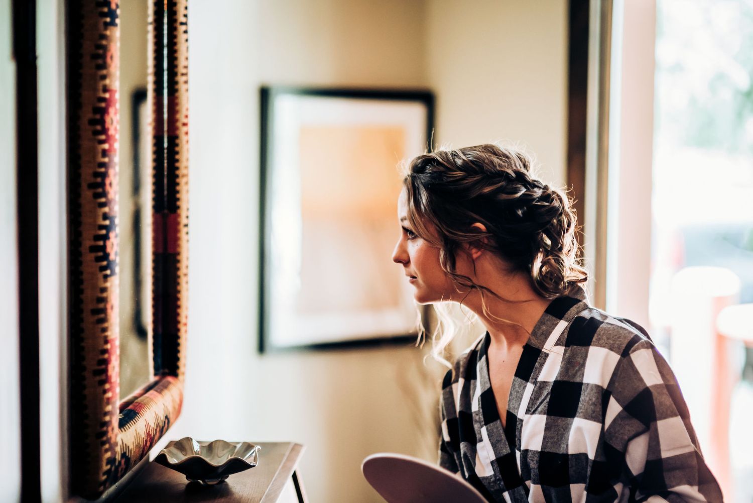 Wedding preparation moment in natural window light with black and white plaid shirt.