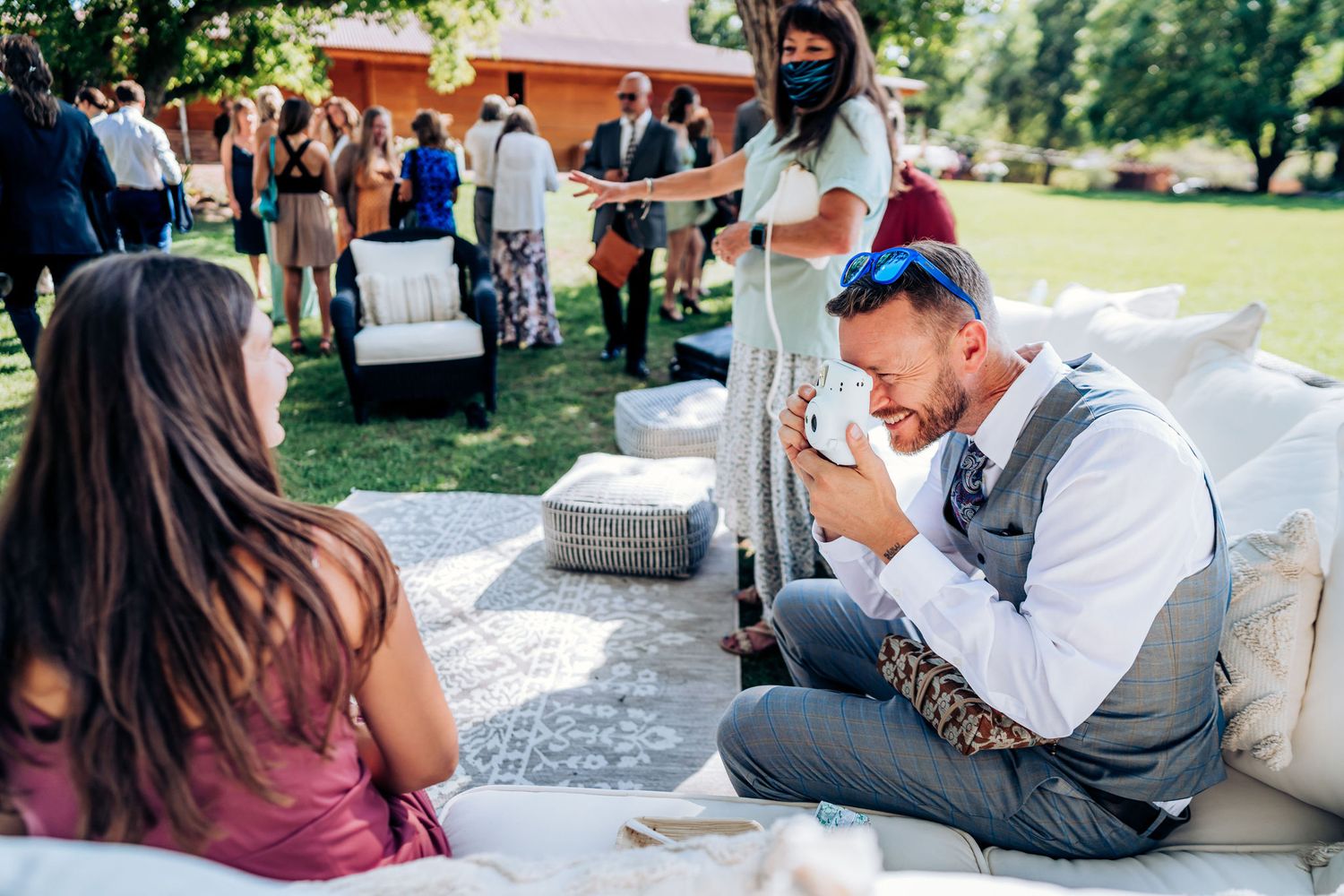 Emotional moment captured during outdoor wedding reception with guests seated on white lounge furniture.