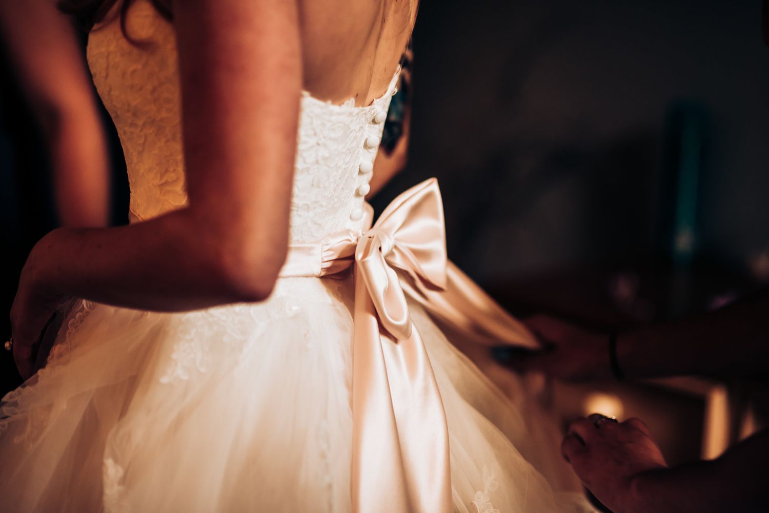 Close up detail shot of white wedding dress with large decorative bow on the back.