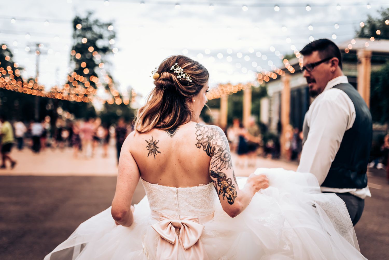 Dancing couple celebrating at outdoor wedding reception under string lights.