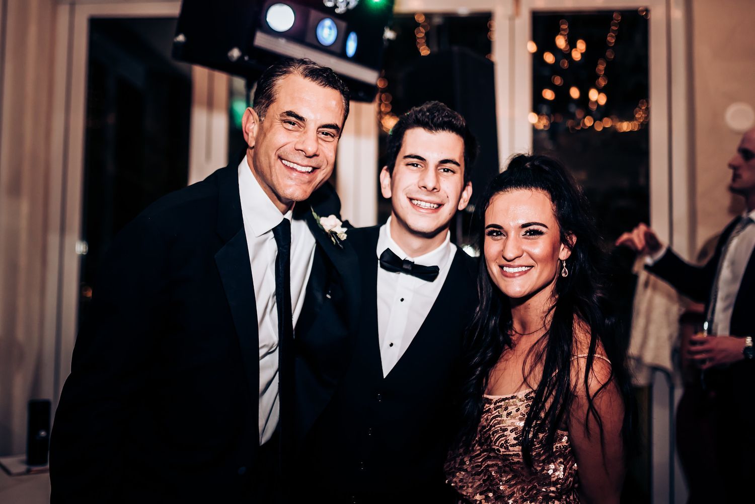 Three guests pose together at a formal event wearing elegant evening attire.