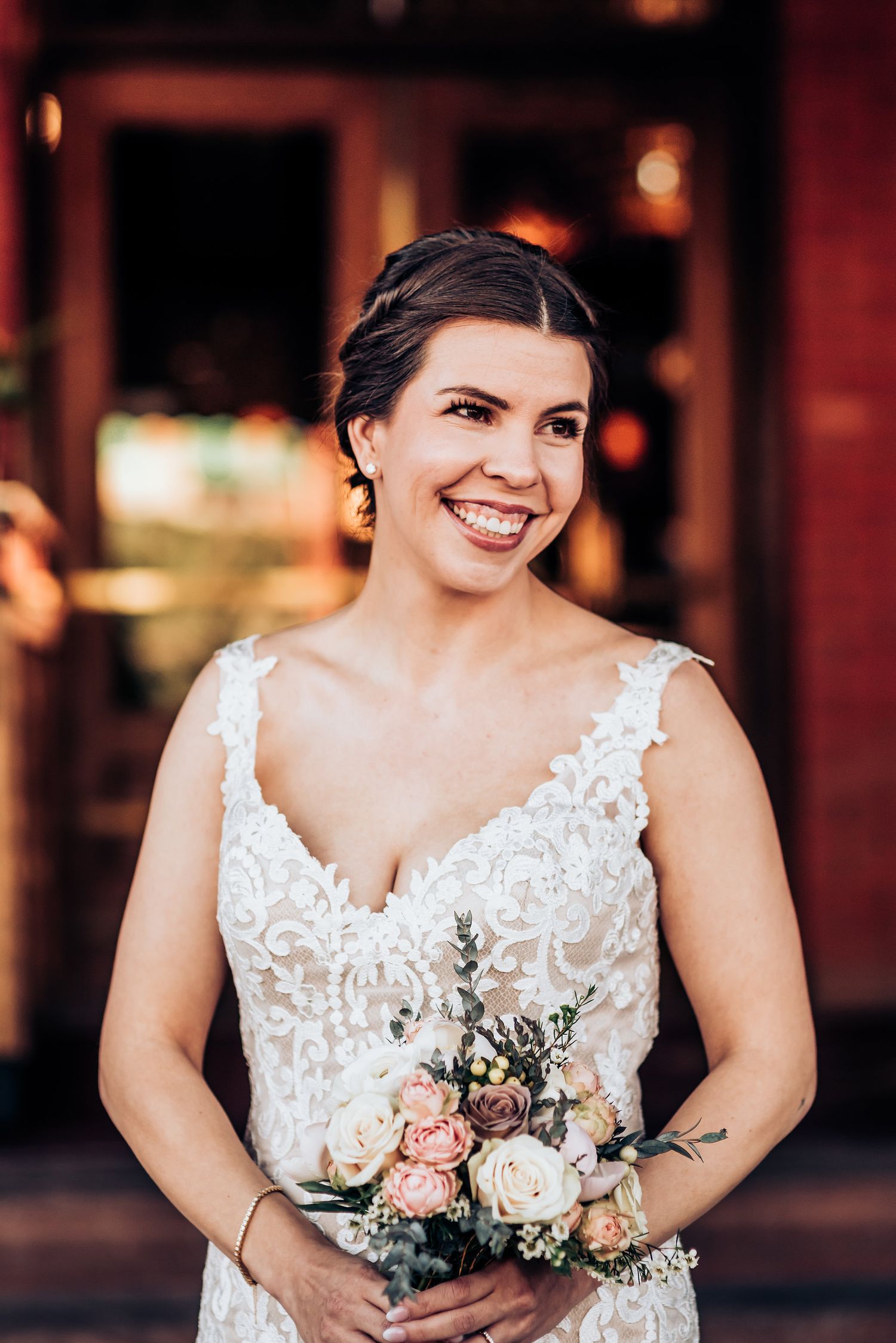Elegant wedding portrait with delicate lace dress and soft pastel bouquet.