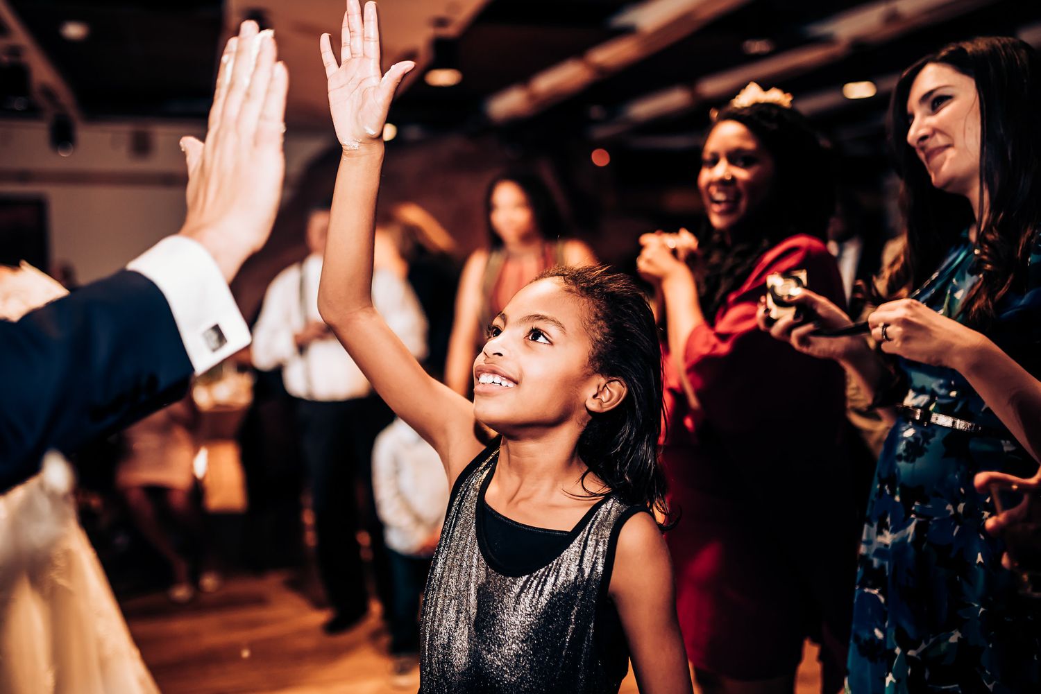 Young guest dancing with raised arms on festive reception dance floor.