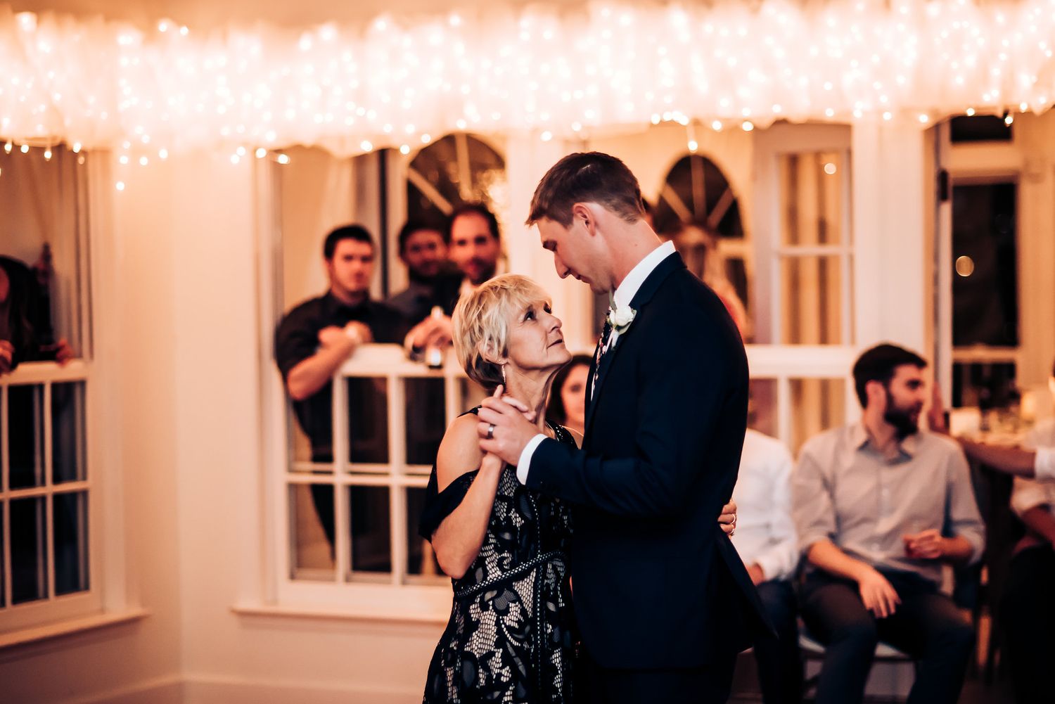 A couple shares a romantic dance at their wedding reception while guests look on.