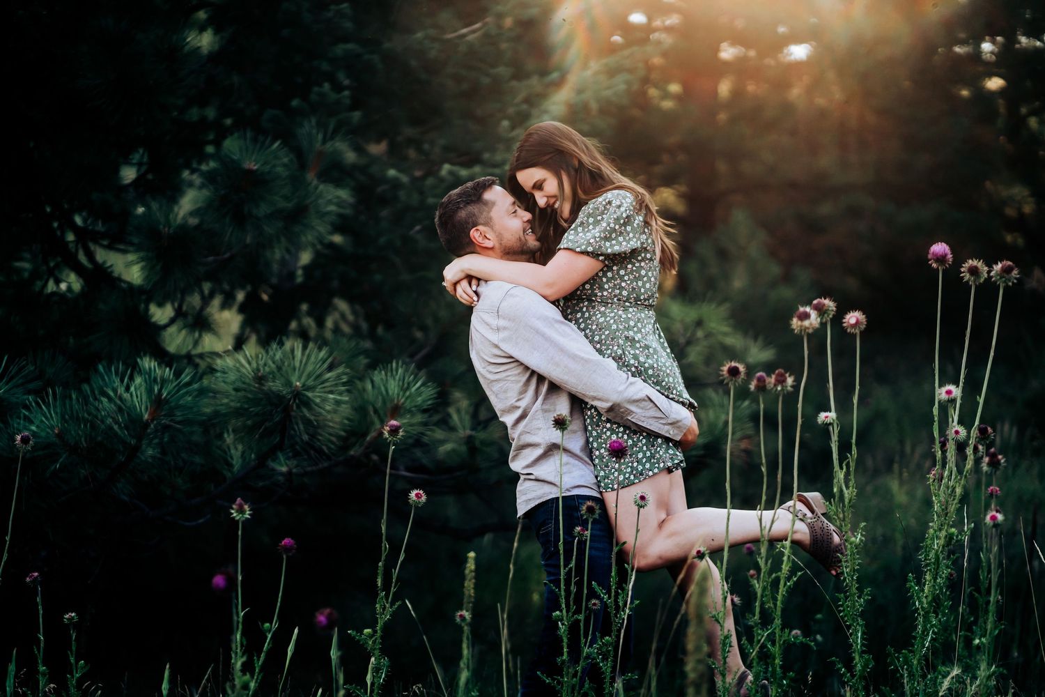 Romantic engagement photo session in a field with tall wildflowers at sunset.