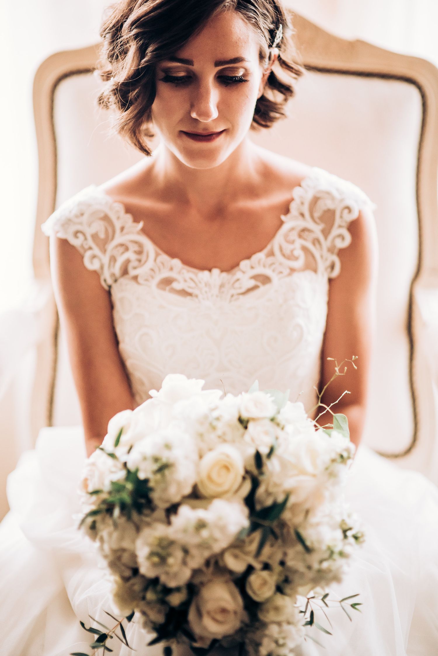 Elegant bridal portrait with white rose bouquet and lace dress details.