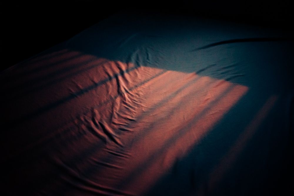 Abstract pattern of red fabric with shadow lines in dark atmospheric lighting.