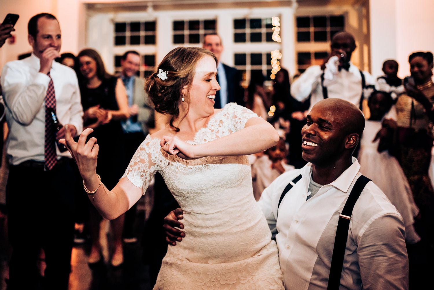 Wedding guests dance joyfully together during a lively reception celebration.