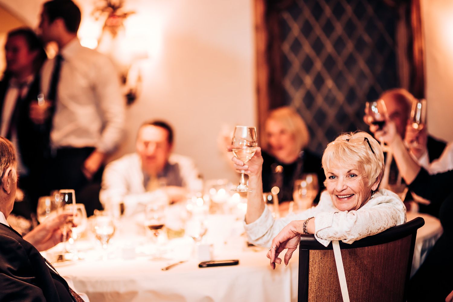 Guests enjoy an intimate candlelit wedding reception dinner in an elegant dining room.
