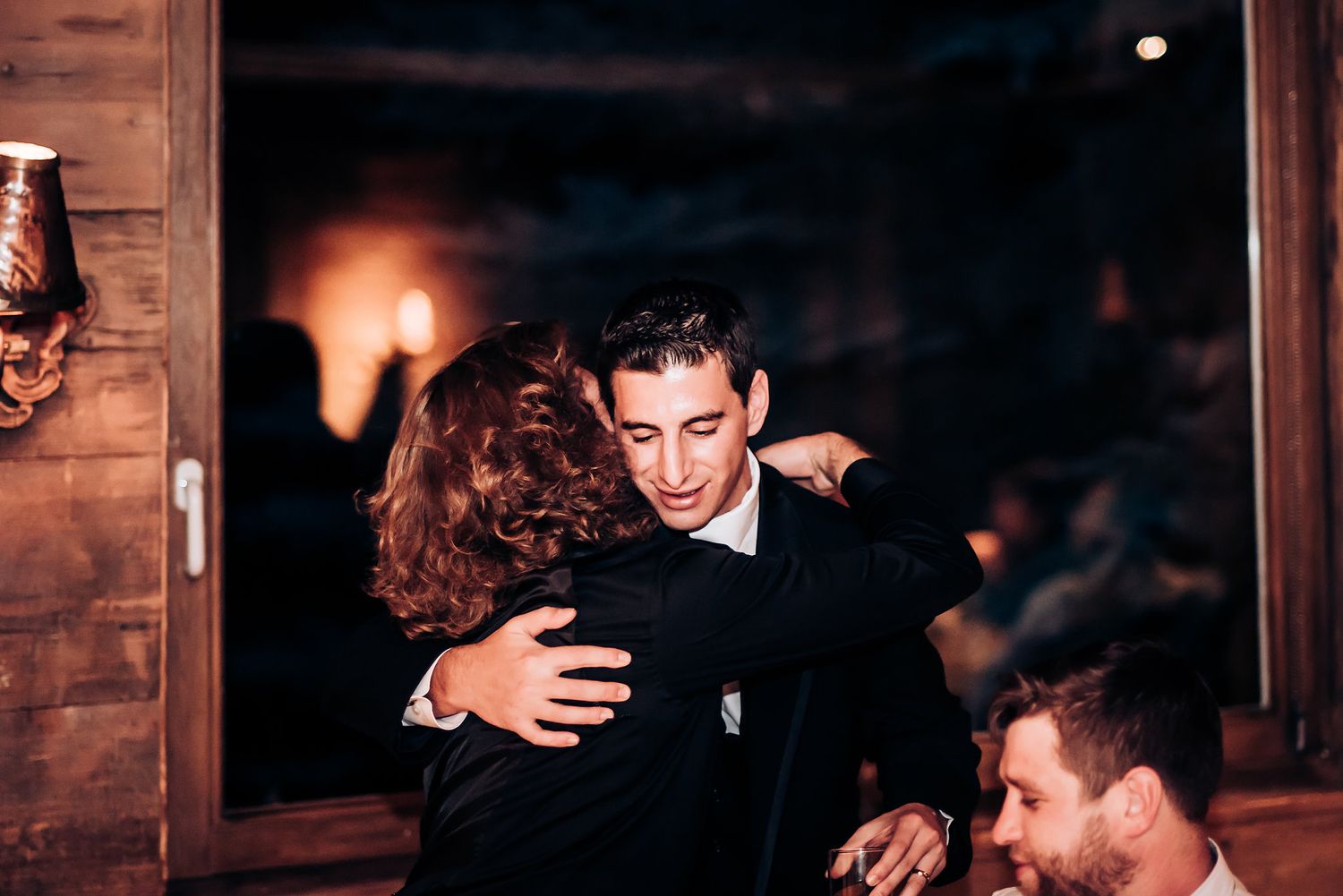Emotional embrace shared during intimate moment at dimly lit wedding reception.
