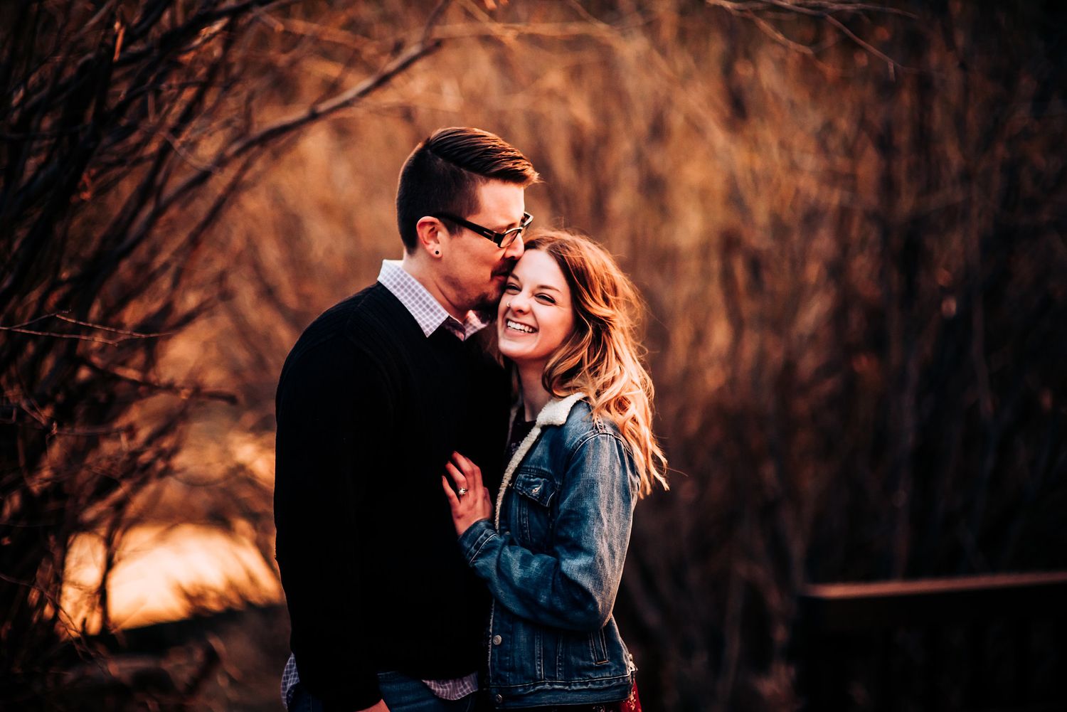 Couple sharing intimate moment at sunset with warm backlighting.