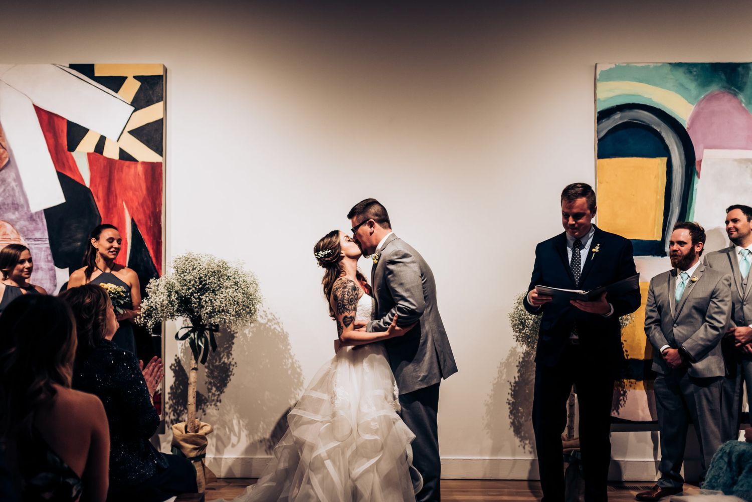 Wedding ceremony in an art gallery with modern decor and baby's breath floral arrangements.