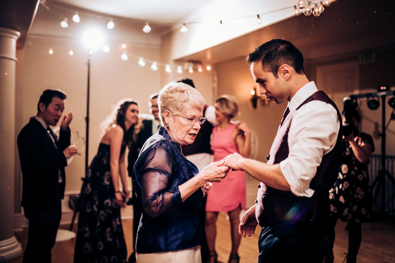 Guests dancing together at an elegant wedding reception with ambient lighting.