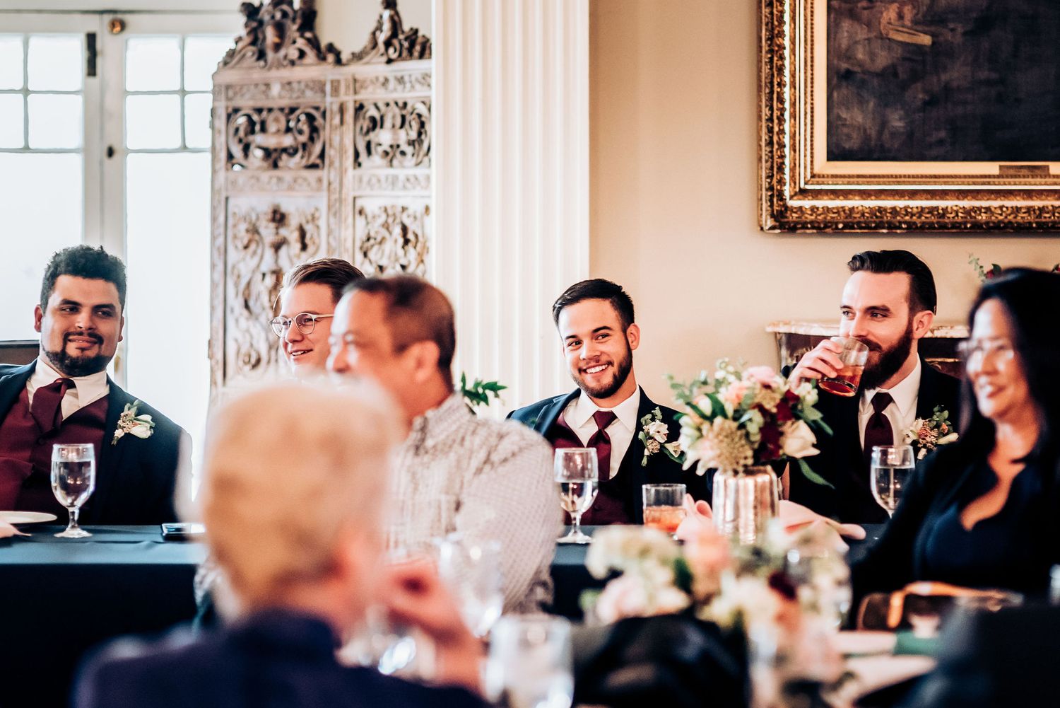Wedding guests laugh and share stories during an elegant reception dinner gathering.