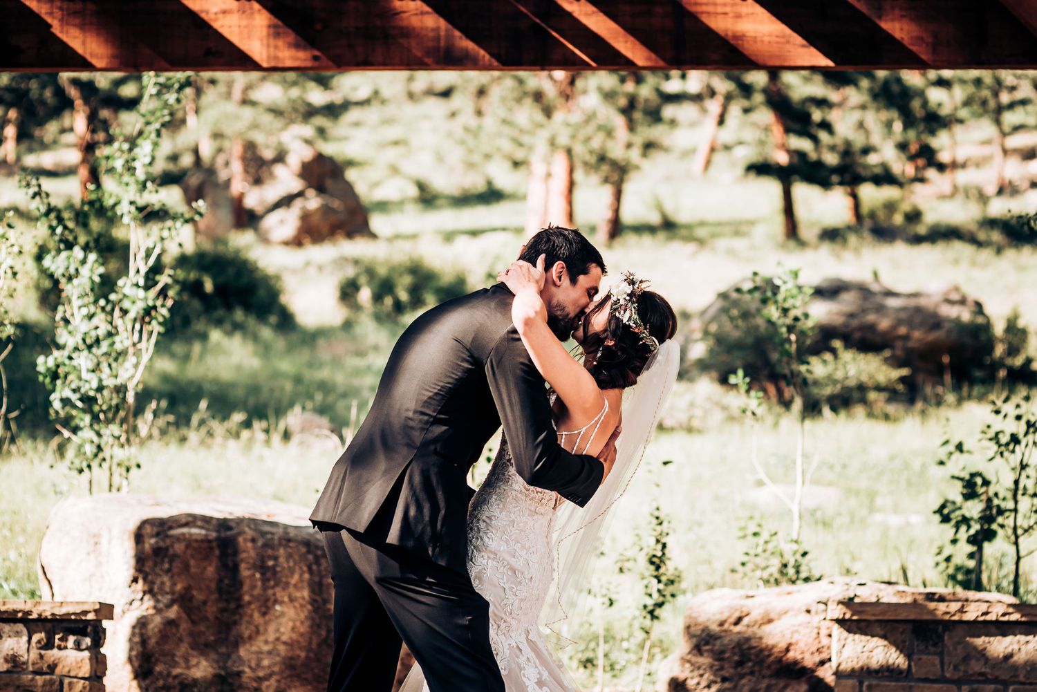 Romantic outdoor wedding moment with sunlit mountain landscape in background.