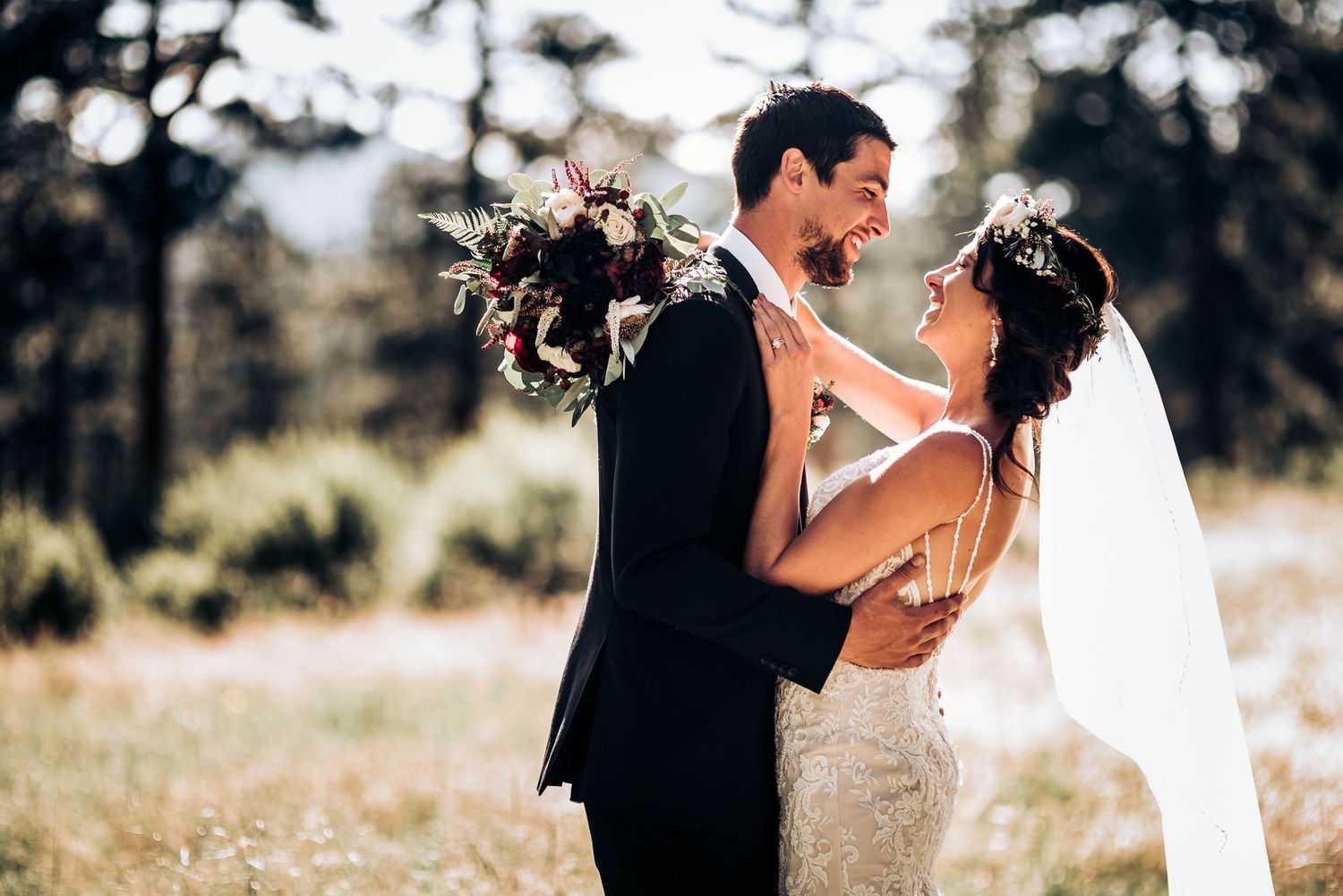 A romantic embrace between newlyweds in a sunlit forest meadow.
