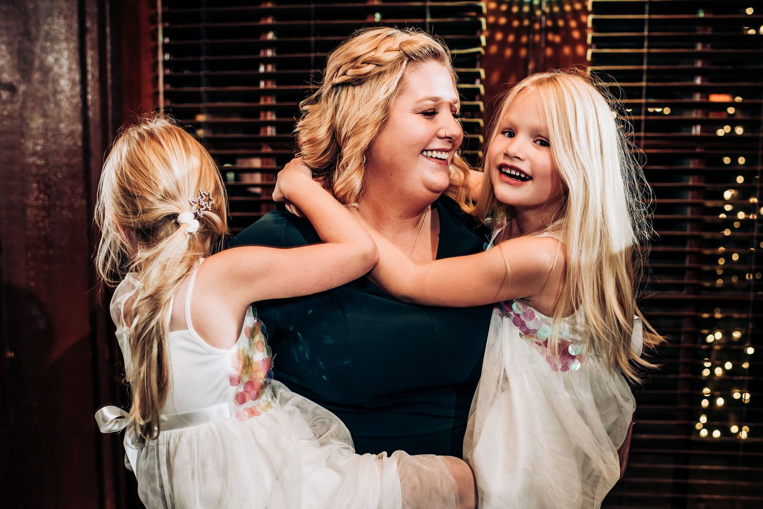 A heartwarming embrace shared during a celebration with twinkling lights in the background.