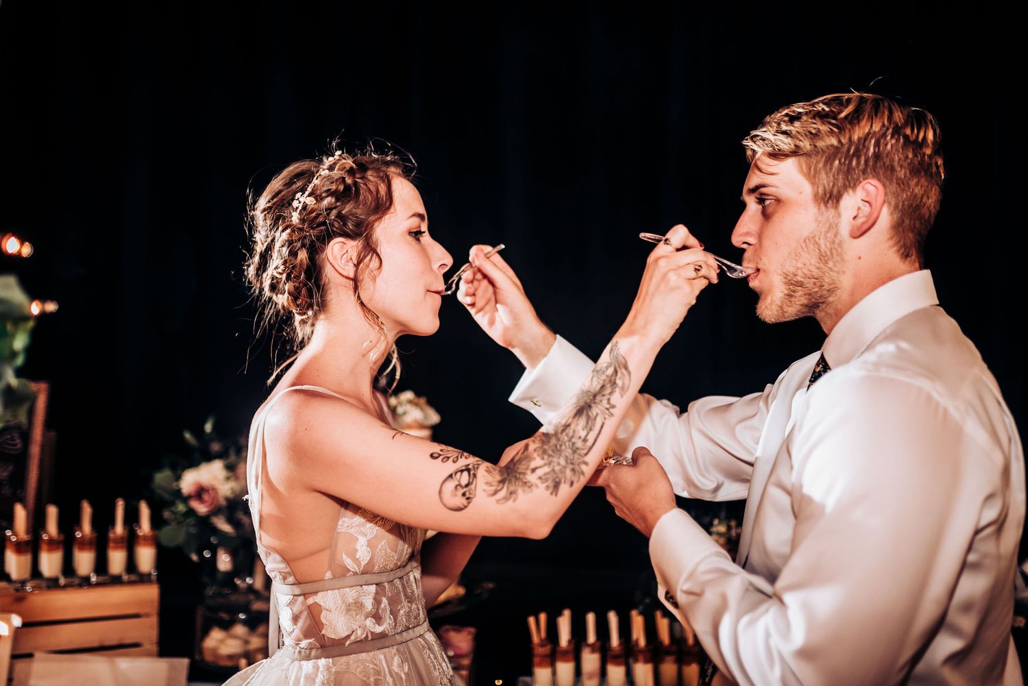 Bride and groom share a fun moment feeding each other dessert at their wedding reception.