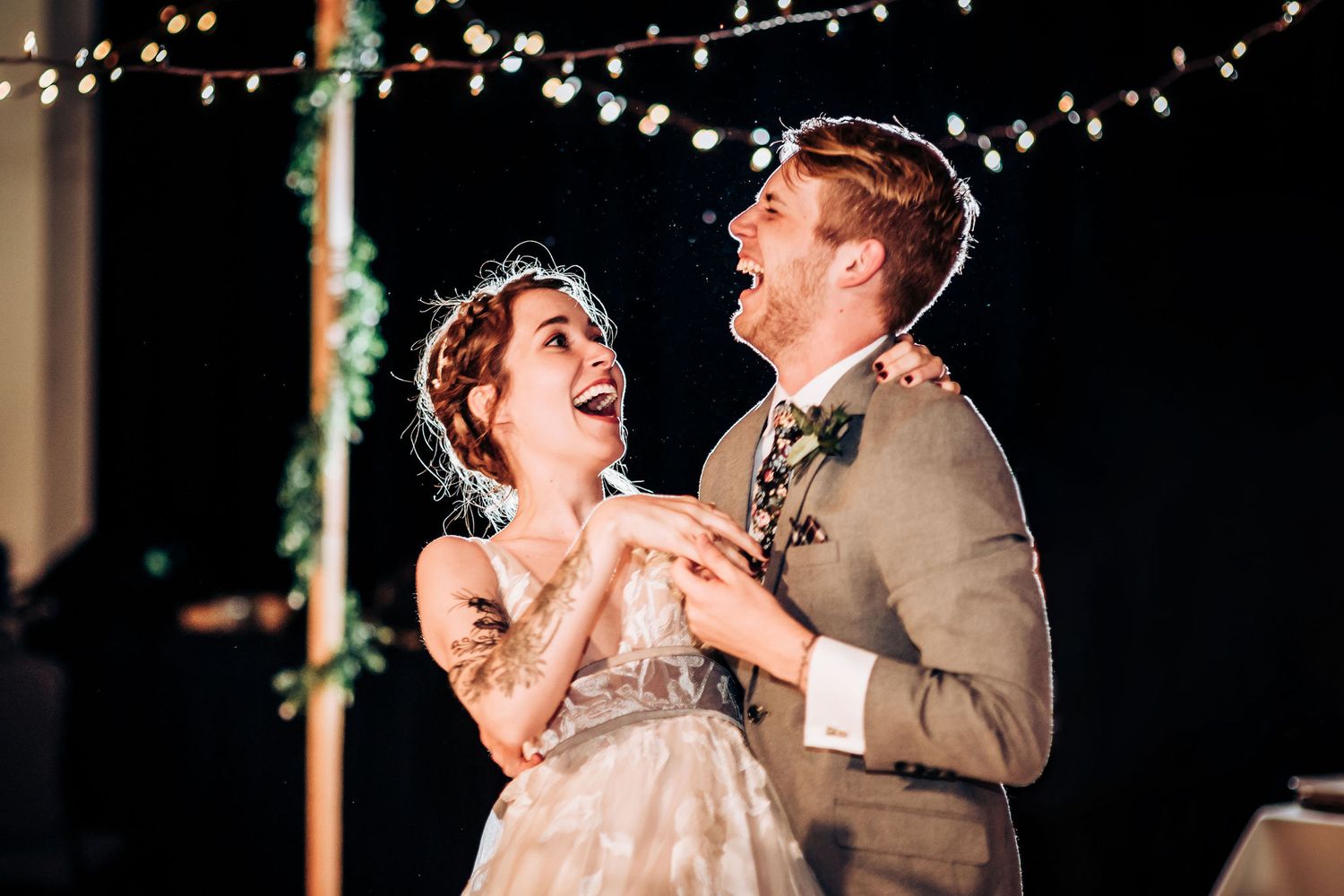 A joyful couple laughing while dancing together at their wedding celebration.