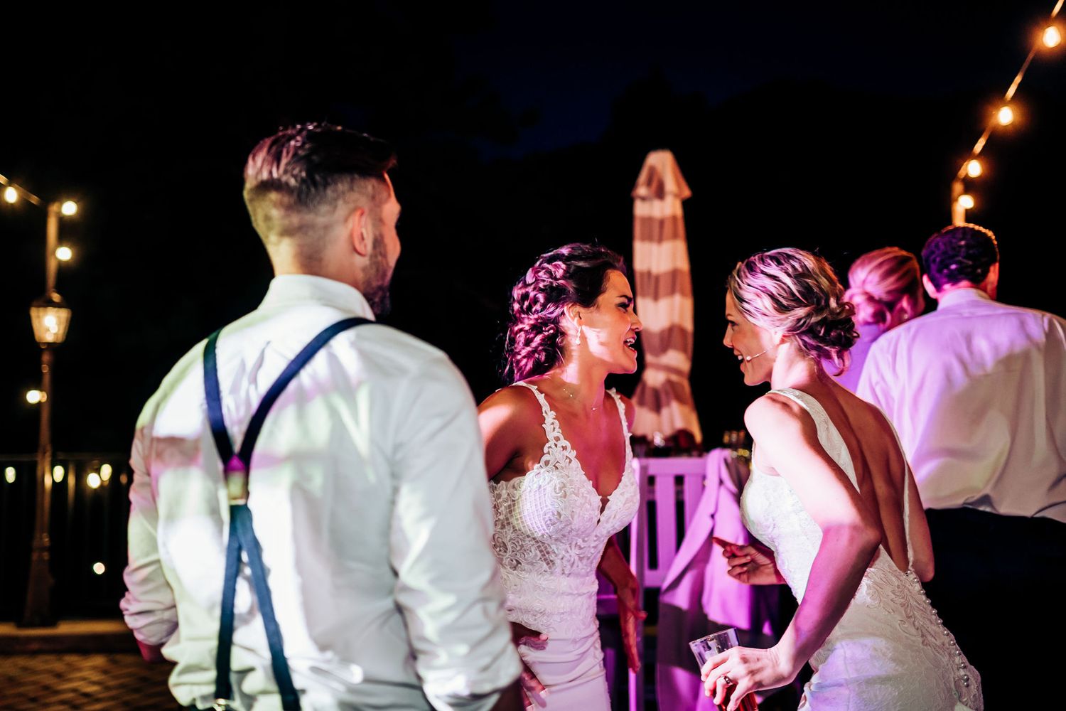 Wedding guests enjoying a lively nighttime celebration under string lights at an outdoor reception.