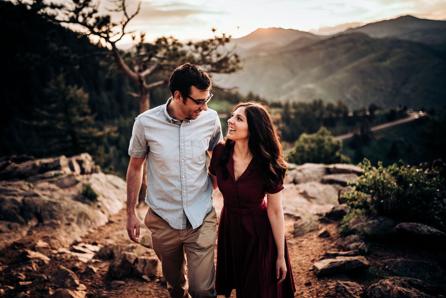 Couple walking together on rocky mountain path during golden hour.
