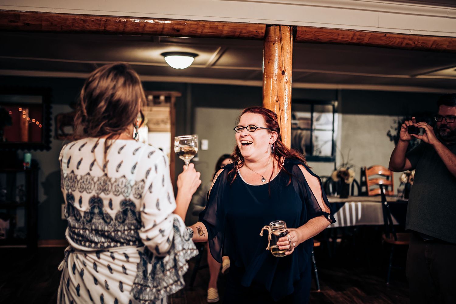 Two guests enjoying conversation and laughter during a celebratory indoor event.