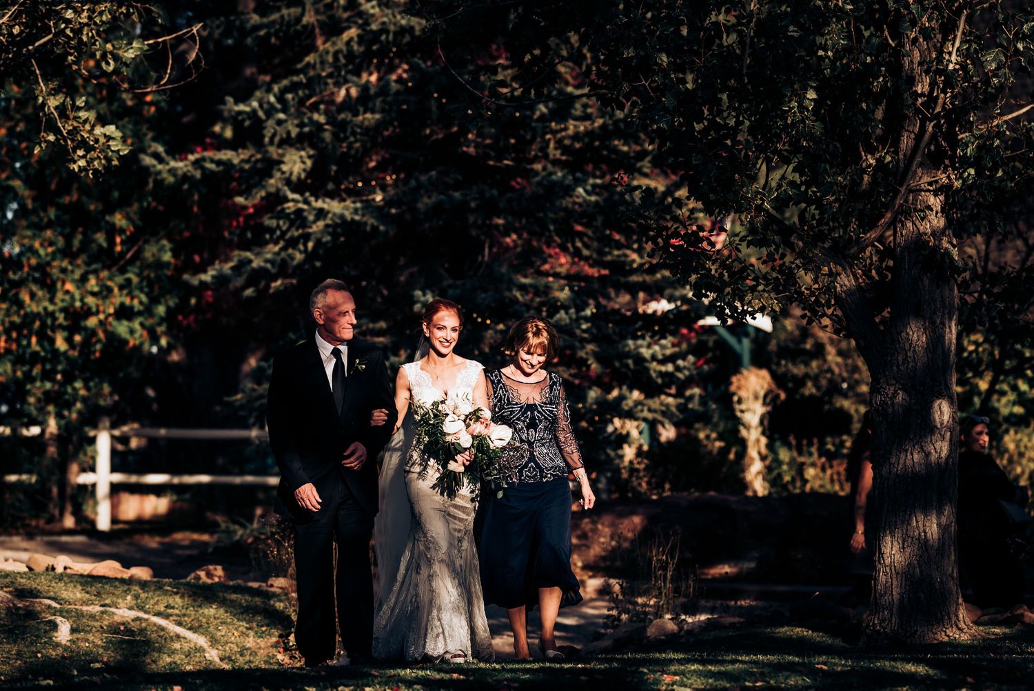 Wedding party walking through a wooded outdoor ceremony setting in autumn.