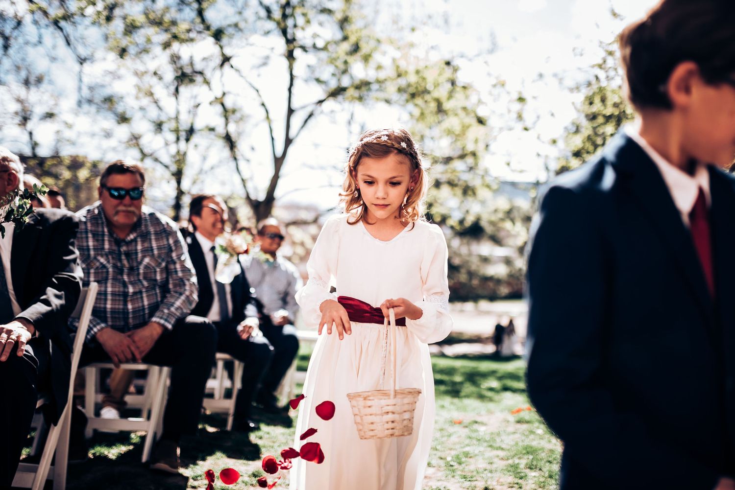 Flower petals scatter along outdoor wedding ceremony aisle during springtime celebration.