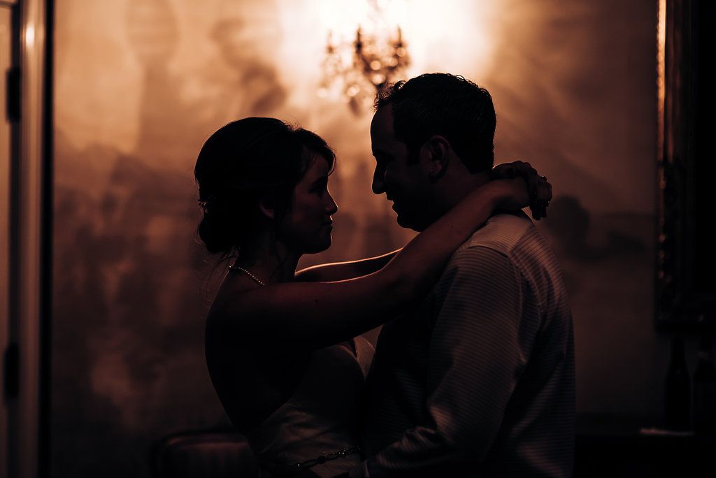 Romantic silhouette of a couple embracing in dim lighting with warm ambient glow.