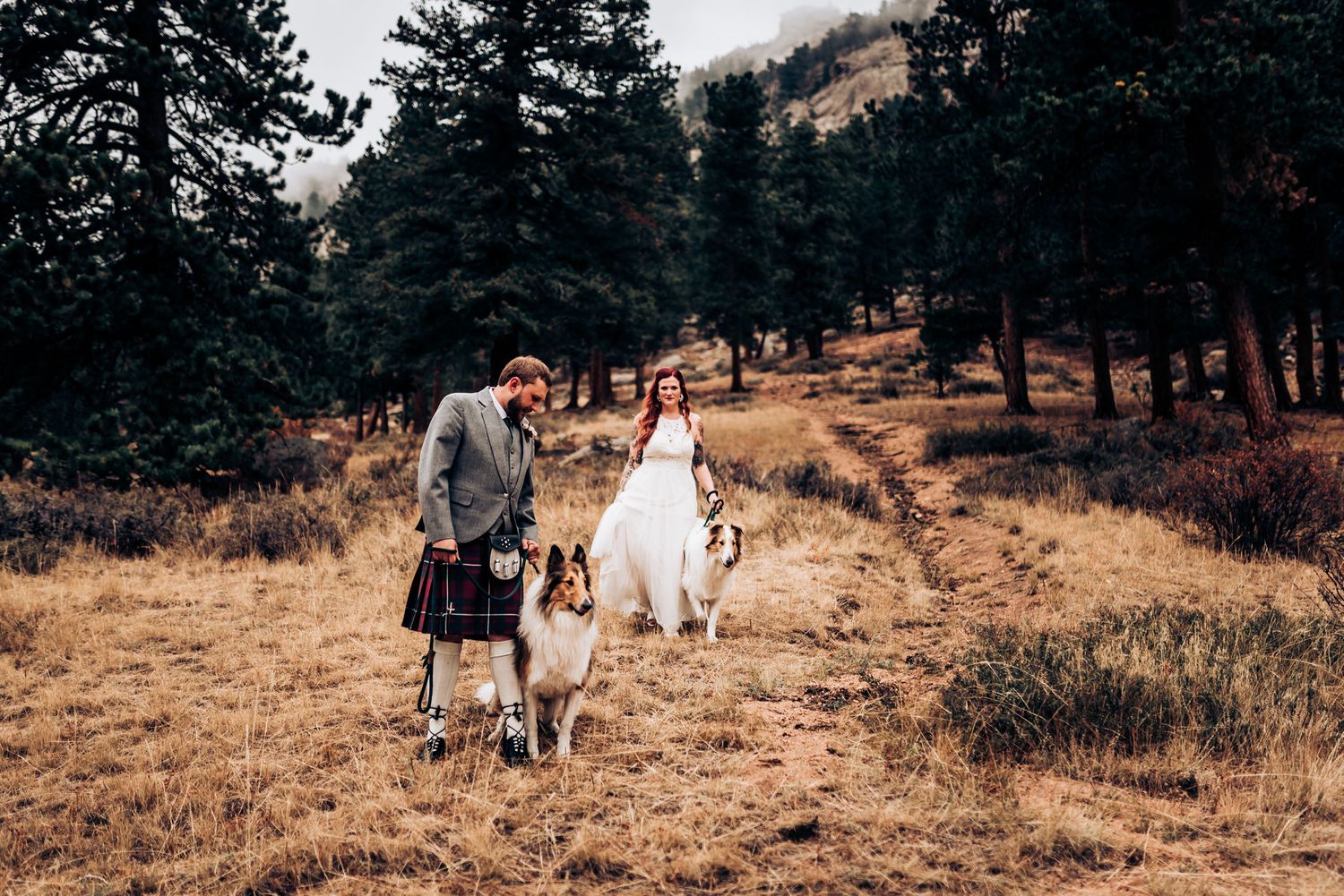 A couple strolls through an autumn mountain landscape with their dogs as they celebrate their wedding day.