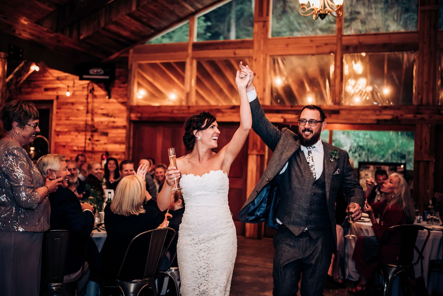 Celebratory moment during wedding reception in rustic wooden barn venue.