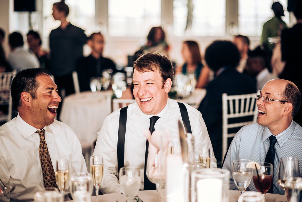 Guests sharing laughter at an elegant wedding reception dinner table.