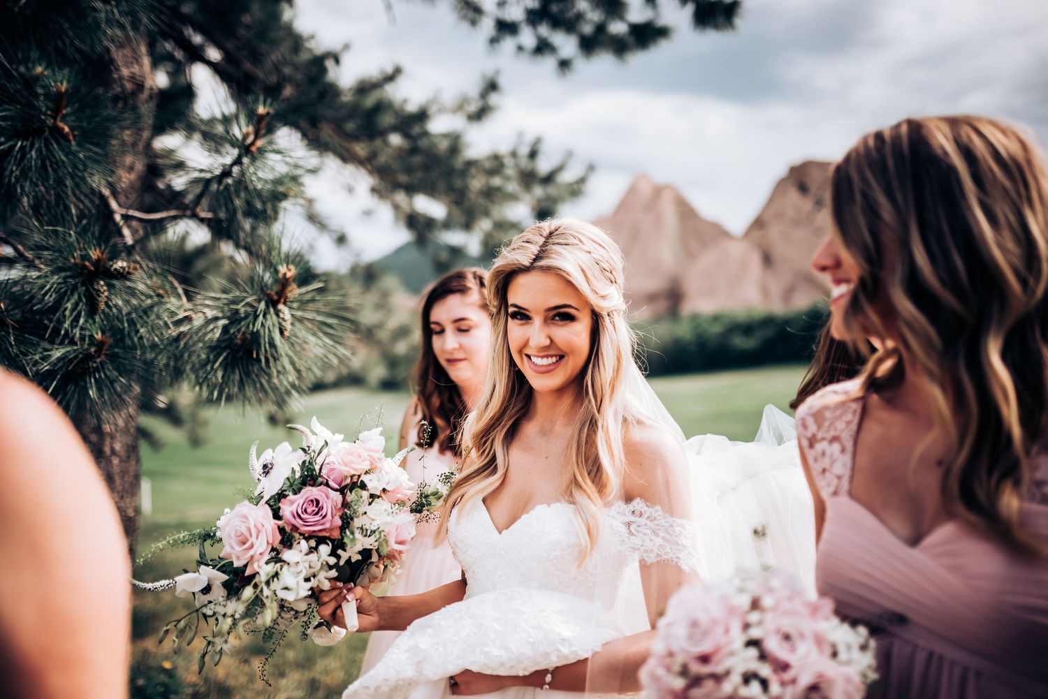 Wedding party with bouquets poses against stunning mountain backdrop.