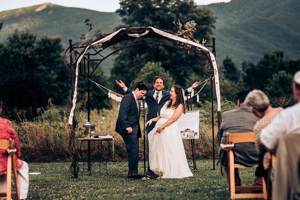 Wedding ceremony under wooden arch with mountain views and seated guests in attendance.