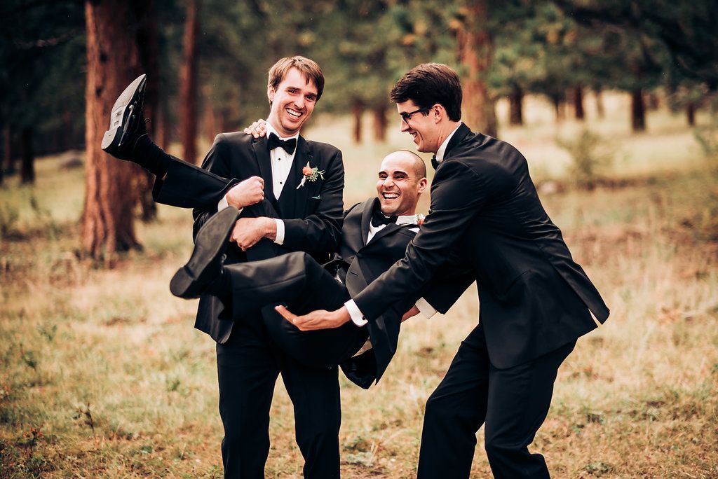 Groomsmen share playful moment during outdoor wedding photoshoot.