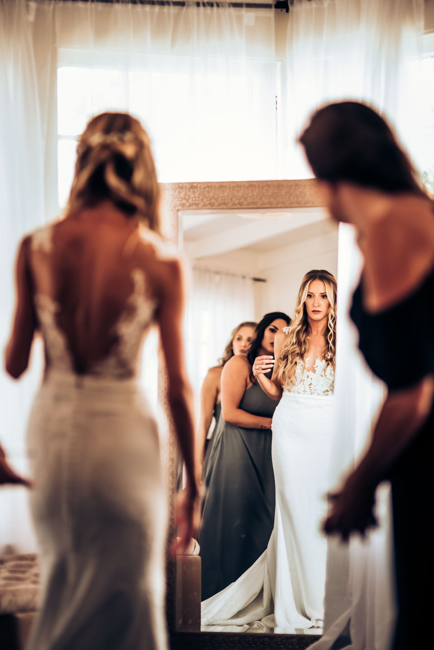 Bridal party looks at their reflections in a mirror during wedding preparations.