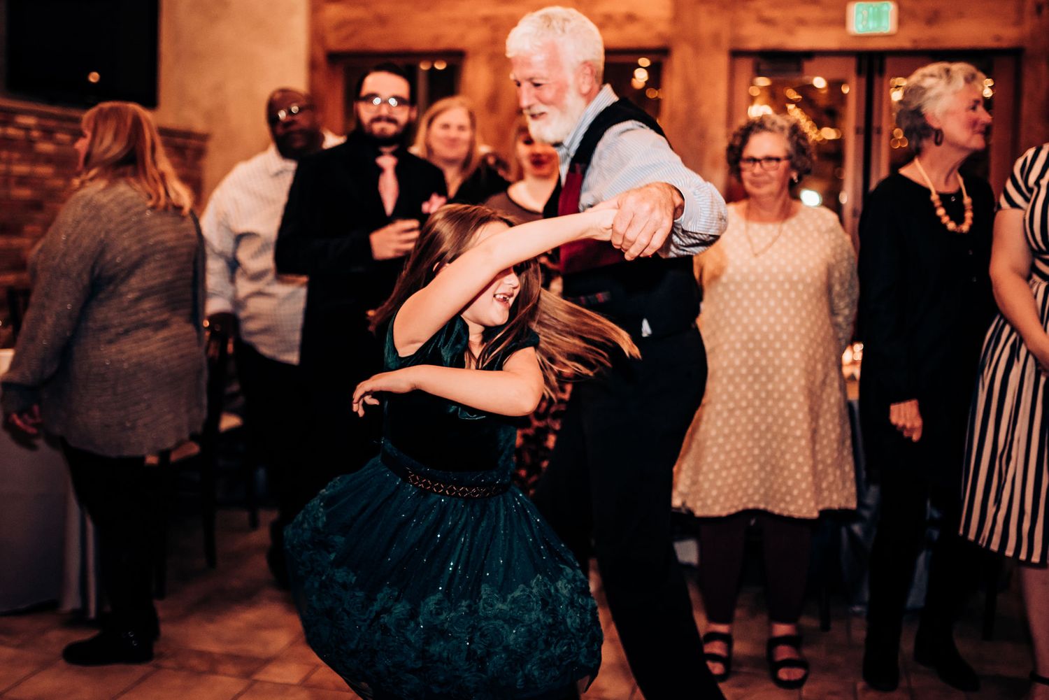 Guests dancing and celebrating on the dance floor at evening wedding reception.
