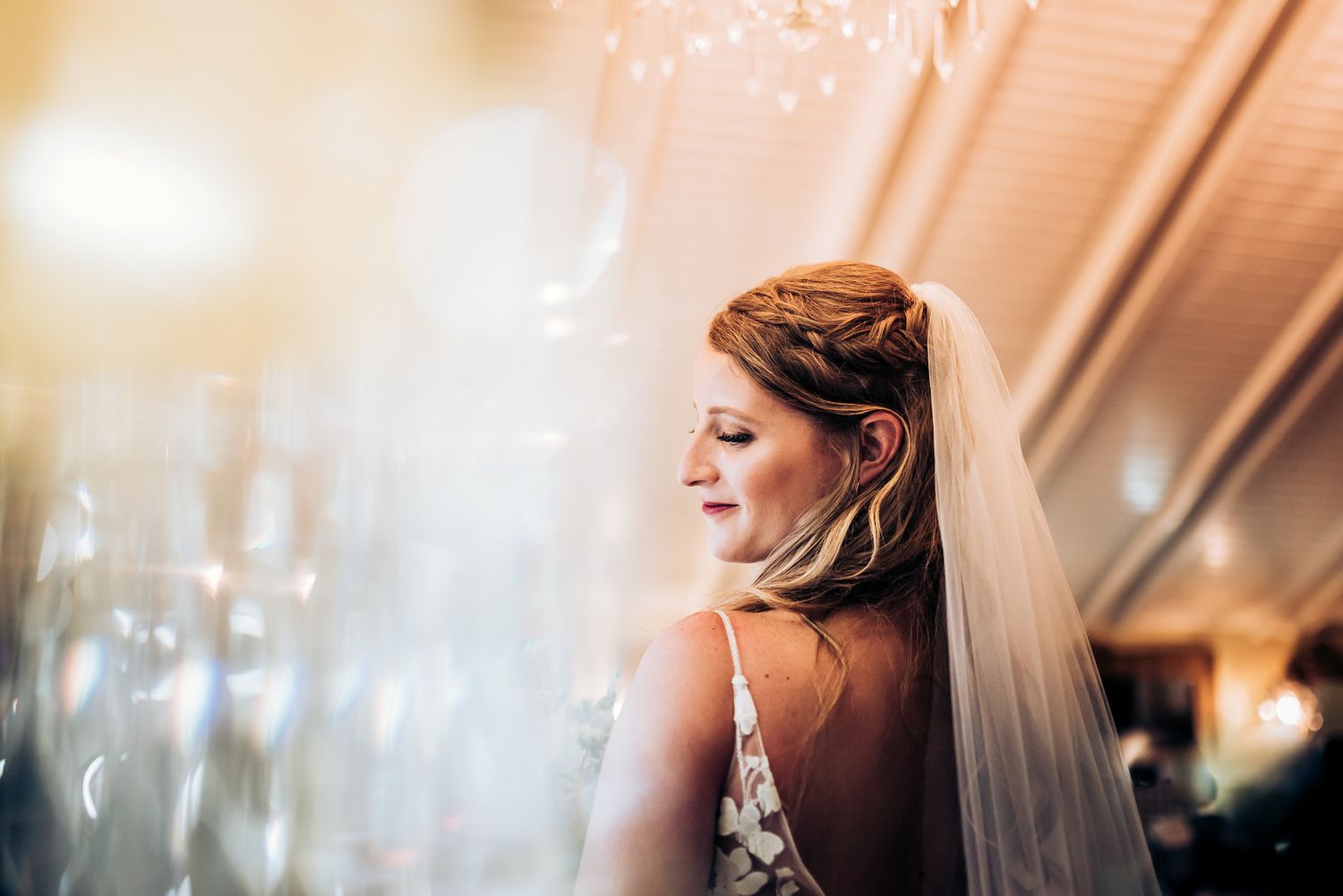 Ethereal side profile of bride with flowing veil under soft lighting.