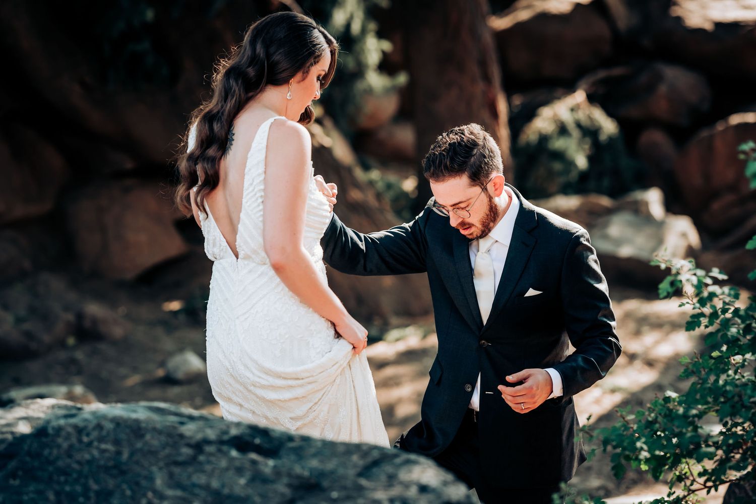 A romantic wedding moment captured outdoors with elegant white dress and dark suit against a natural backdrop.