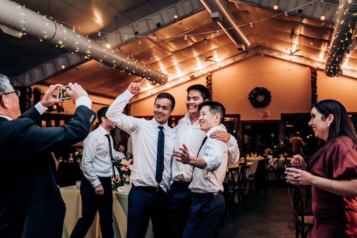 Wedding guests enjoying drinks and celebrating enthusiastically on the dance floor.