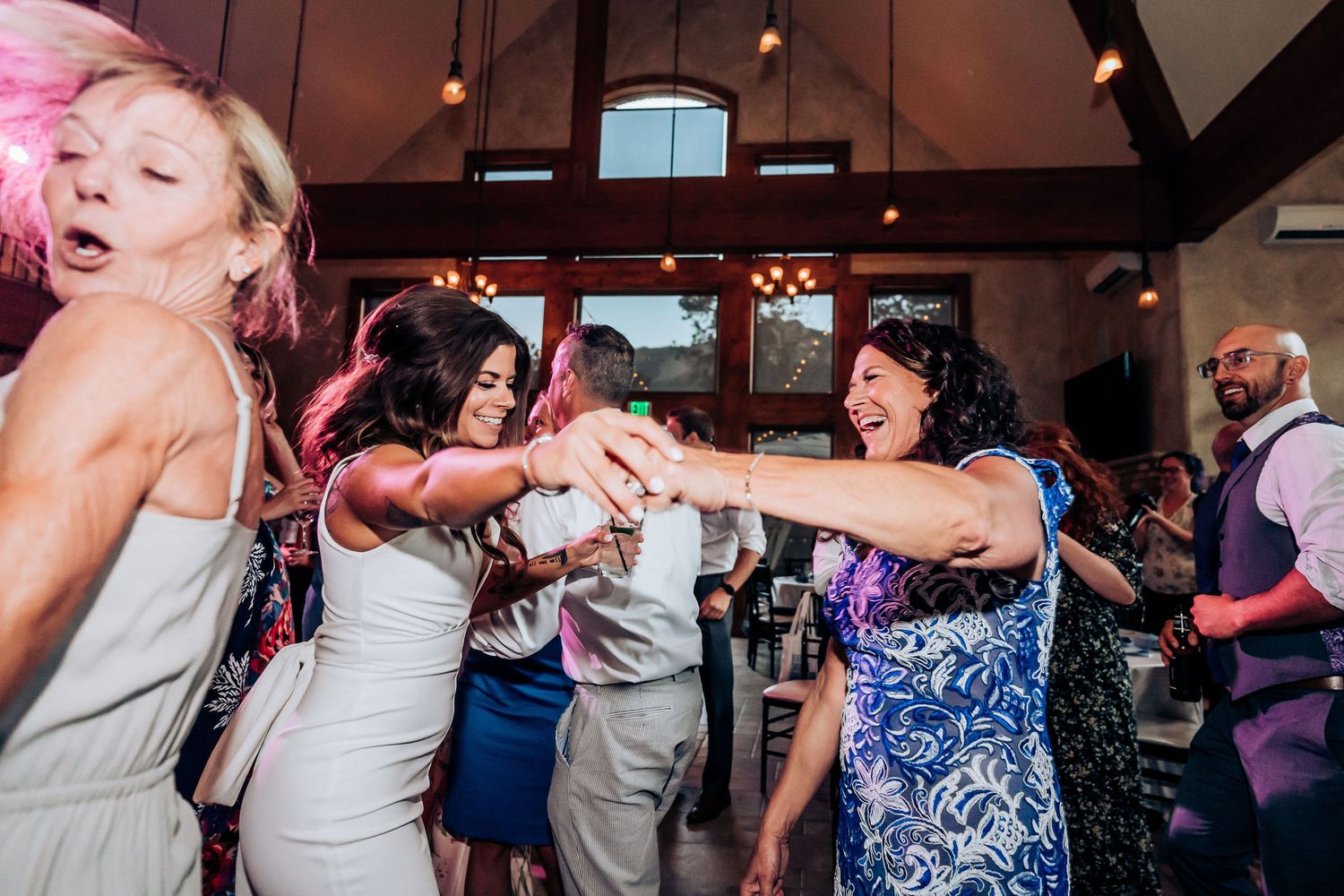 Enthusiastic party guests in colorful attire dancing and celebrating on the dance floor.